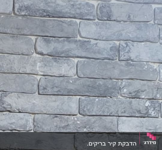 קיר לבנים אפור עם מנורה בתקרה